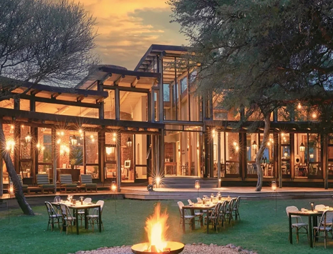 Modern lodge with outdoor fire pit at sunset surrounded by trees